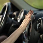 Donna che mette la mano davanti alla bocchetta dell'aria condizionata in auto
