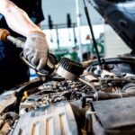 meccanico che mette l'olio ad un'auto