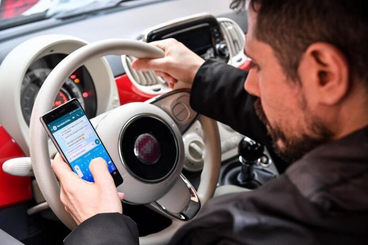 Ragazzo che apre Whatsapp in auto