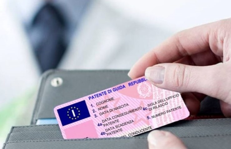 Donna che tira fuori la patente dal portafoglio e medico sullo sfondo