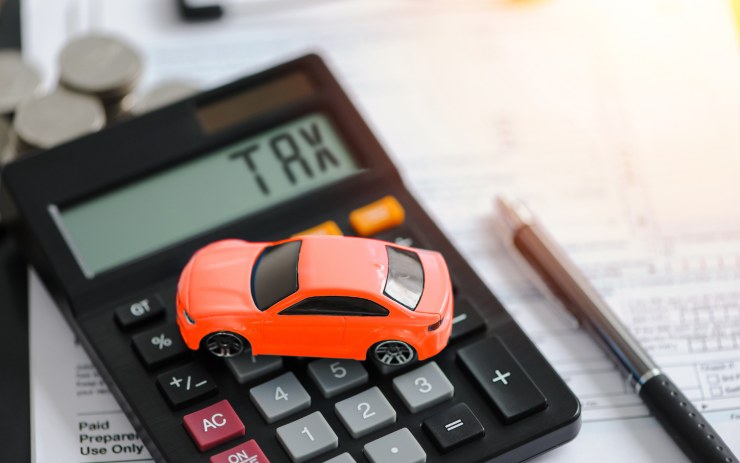piccola auto sopra una calcolatrice con scritto "Tax"