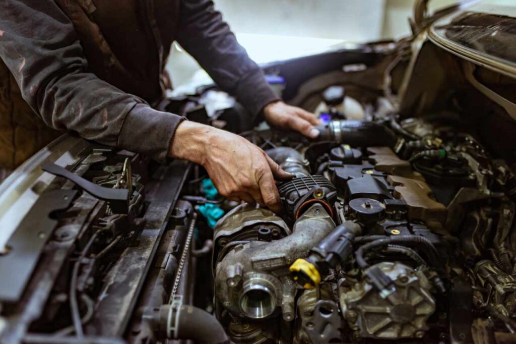 Meccanico che controlla dentro al cofano di un'auto