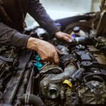 Meccanico che controlla dentro al cofano di un'auto