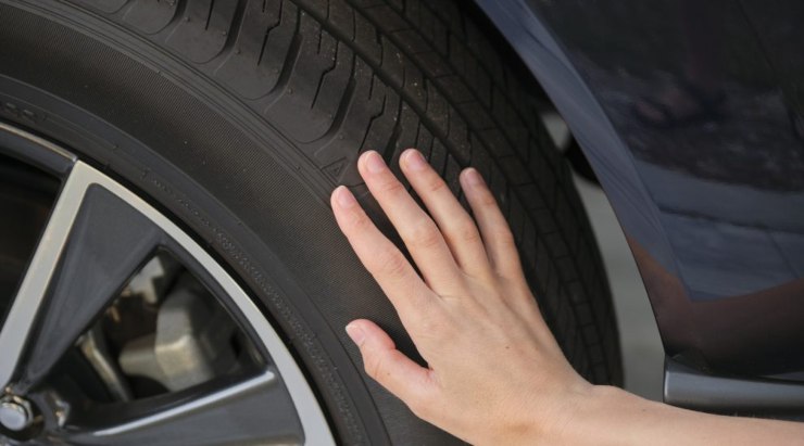 Mano che tocca una gomma dell'auto
