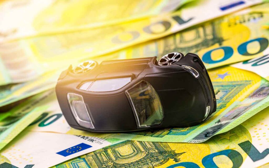 modellino auto ribaltata sopra banconote euro