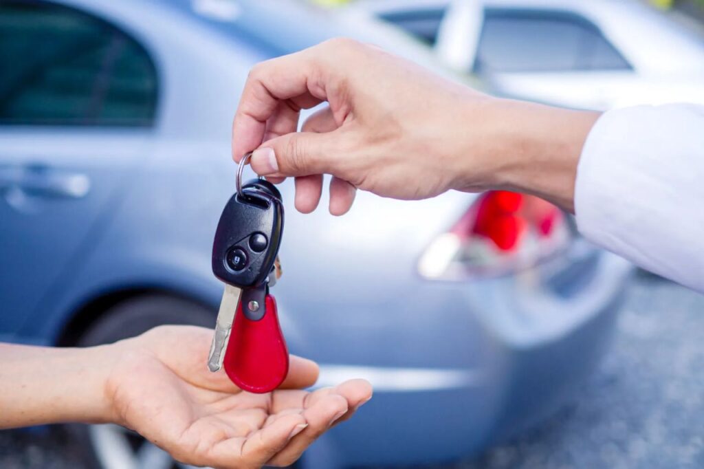 Uomo che dà le chiavi dell'auto ad un altro conducente: vendita dell'usato