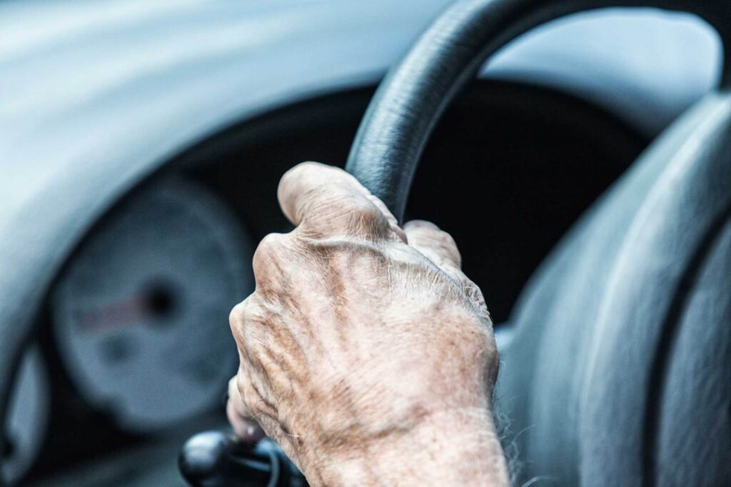 Mano di un'anziana al volante dell'auto
