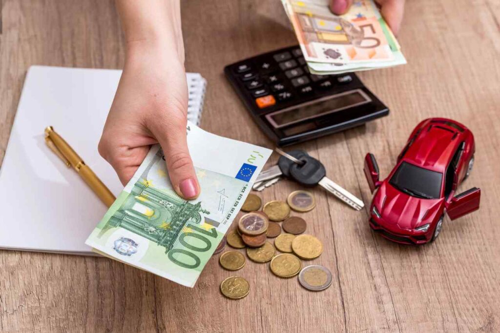 Calcolo spese auto: macchina in miniatura, calcolatrice e banconote euro