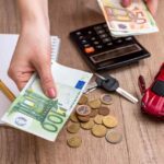 Calcolo spese auto: macchina in miniatura, calcolatrice e banconote euro