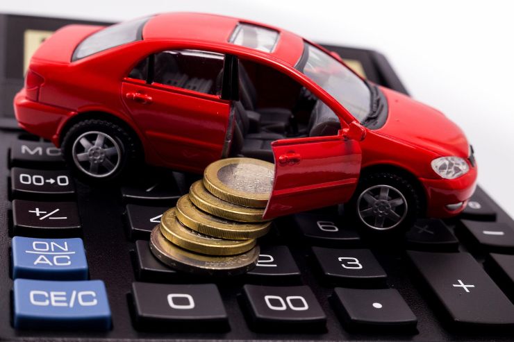modellino auto sopra calcolatrice e monete da un euro che escono dalla portiera