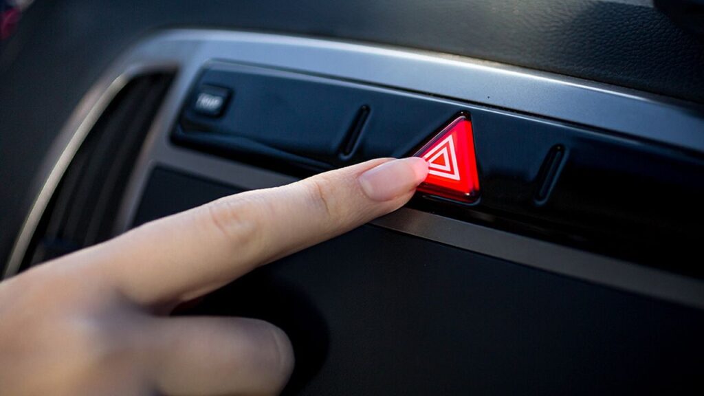 donna che schiaccia le quattro frecce dell'auto