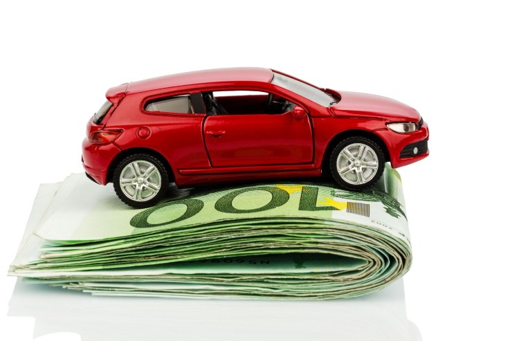 Modellino auto rossa sopra mazzetta da 100€