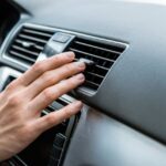 Mano davanti alla bocchetta dell'aria di un'auto