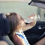 Ragazza che beve una bottiglietta d'acqua alla guida