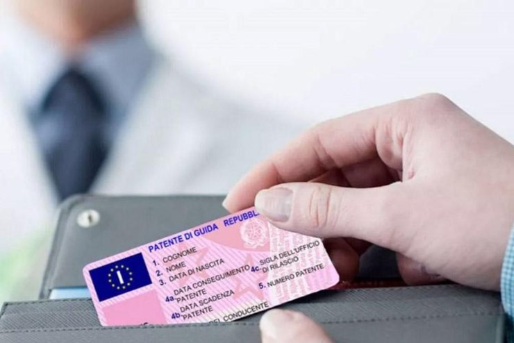Donna che tir fuori dal portafoglio la patente di guida. Medico sullo sfondo