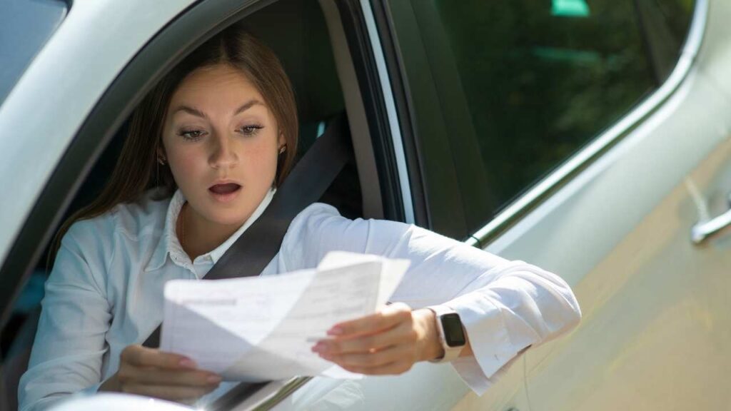 Ragazza alla guida che legge il foglio assicurativo