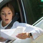 Ragazza alla guida che legge il foglio assicurativo