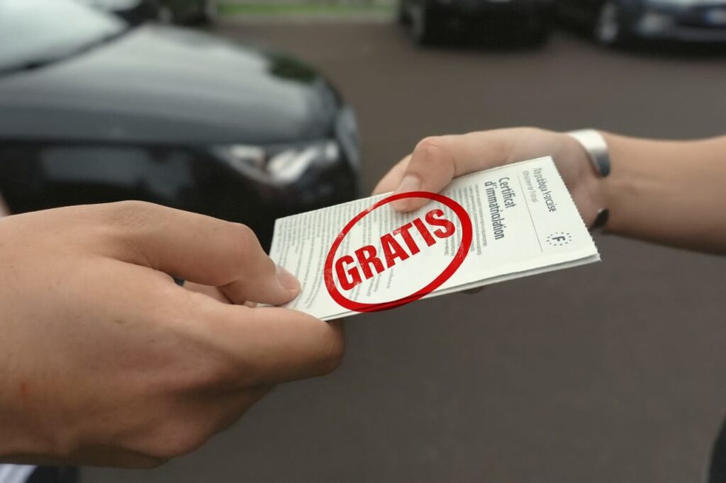 Due persone che si scambiano il passaggio con auto sullo sfondo. Timbro rosso con scritto "gratis"