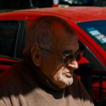 Anziano in primo piano e auto sullo sfondo
