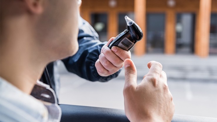 Automobilista che si sottopone all'alcol test dato dall'agente