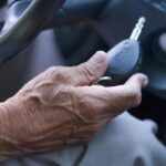 Mano di un anziano in auto con la chiave in primo piano