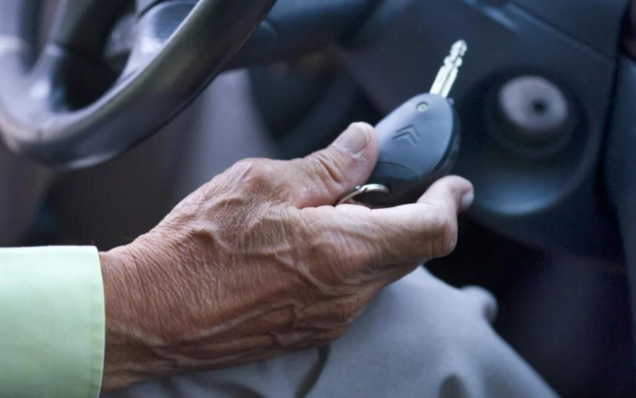 Mano di un anziano in auto con la chiave in primo piano