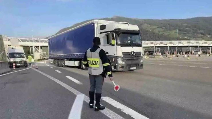 Posto di blocco mezzi pesanti: agente di polizia che ferma un camion con la paletta
