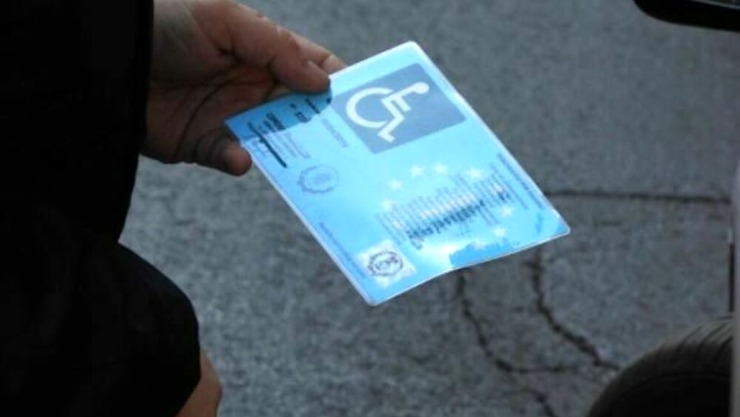 Uomo che tiene in mano il contrassegno auto per disabili