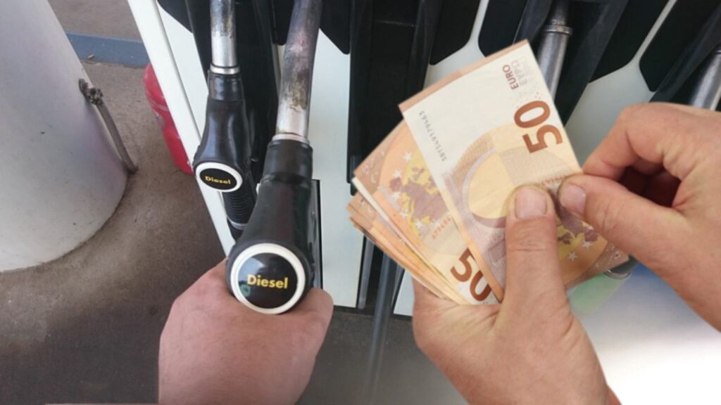 Distributore di benzina e banconote da 50€ in mano a un uomo