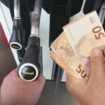 Distributore di benzina e banconote da 50€ in mano a un uomo