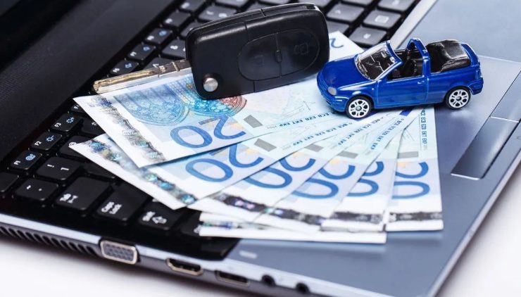 Chiavi auto, banconote da 20€ e auto in miniatura sopra a un pc