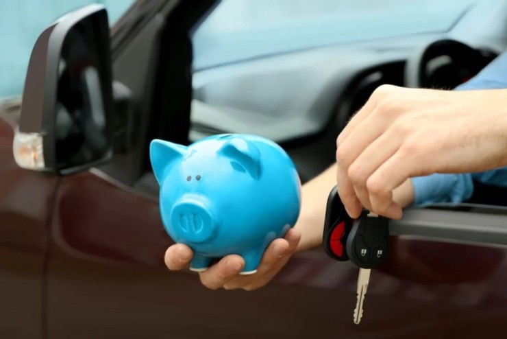 Uomo in auto che tiene in mano chiavi e salvadanaio