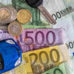 Macchina giocattolo sopra a banconote e monete euro