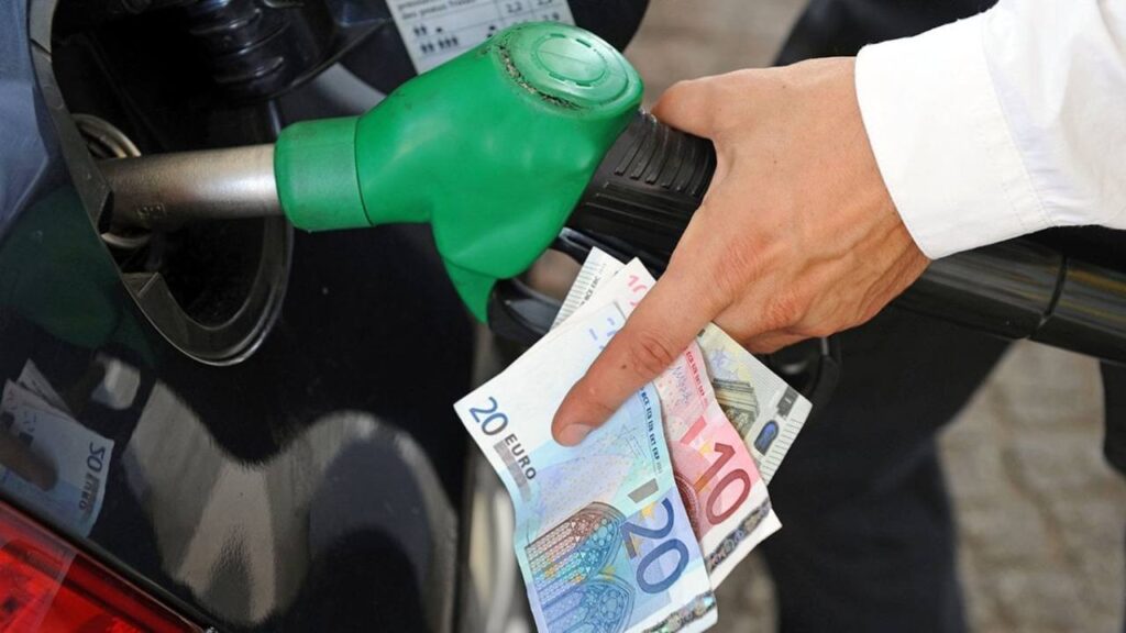 Uomo che fa benzina alla sua auto con pompa e banconote euro in mano