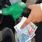 Uomo che fa benzina alla sua auto con pompa e banconote euro in mano