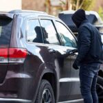 Uomo incappucciato che apre un'auto per rubarla