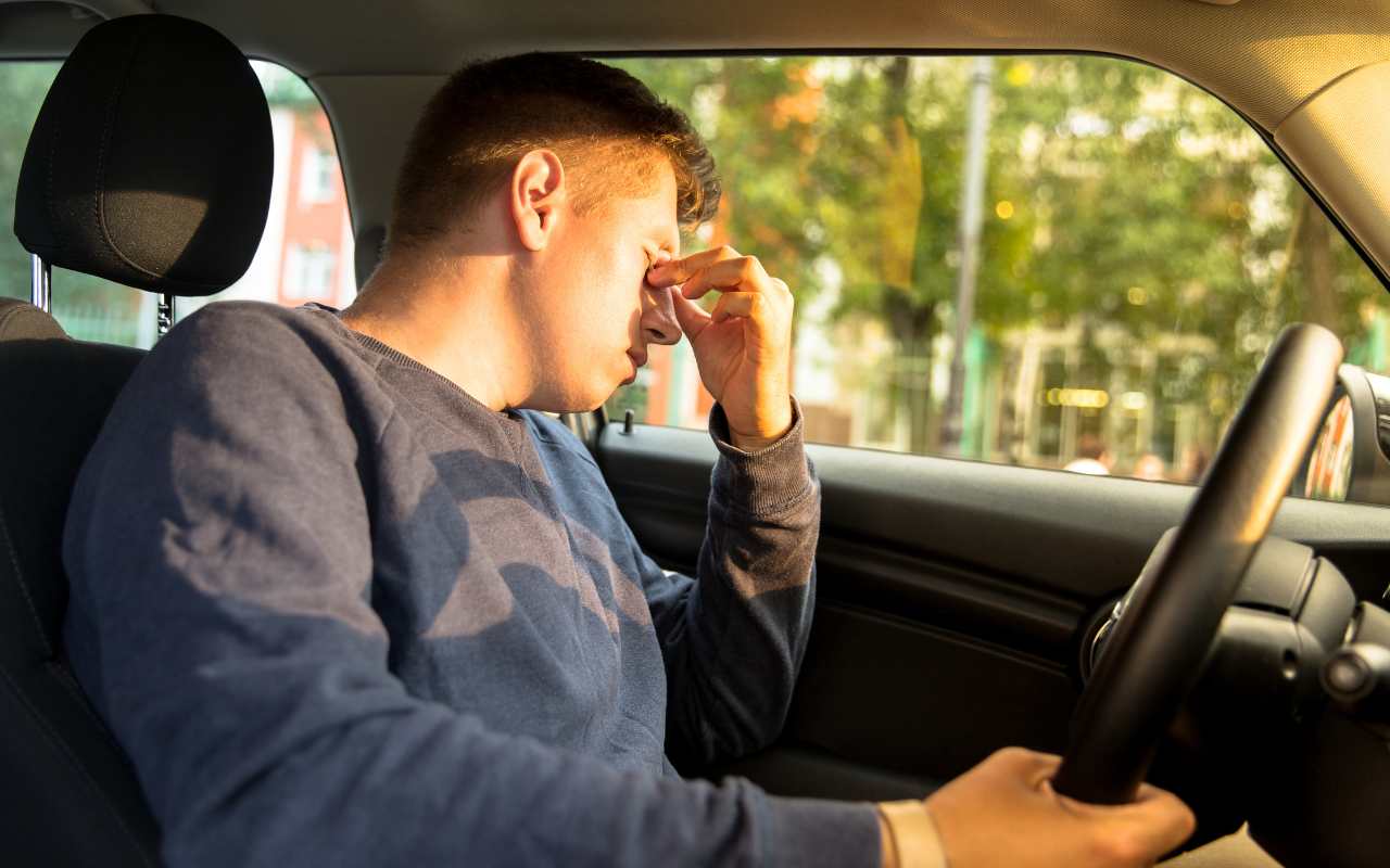 Conducente alla guida di un'auto che si stropiccia gli occhi dal sonno