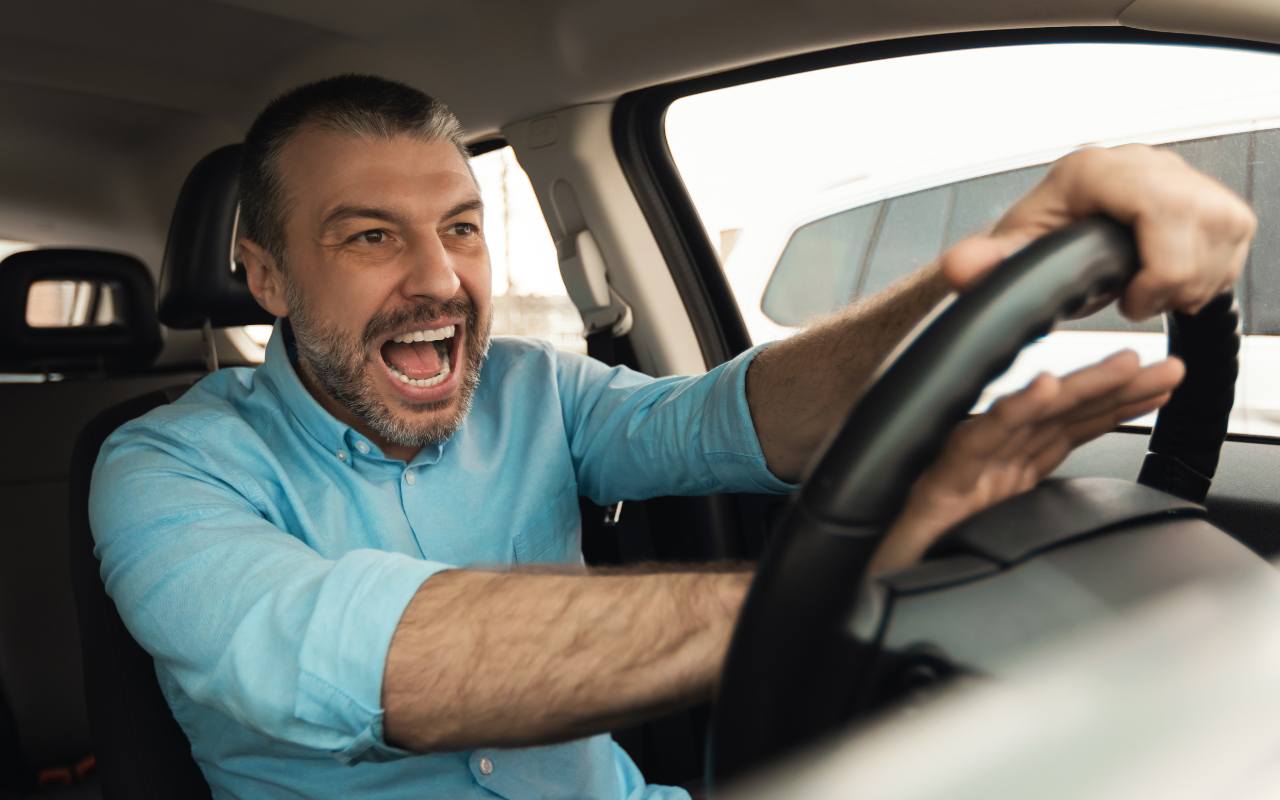 Uomo arrabbiato che schiaccia il clacson della sua auto