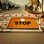 Cartello "stop" retto da transenna in mezzo alla strada