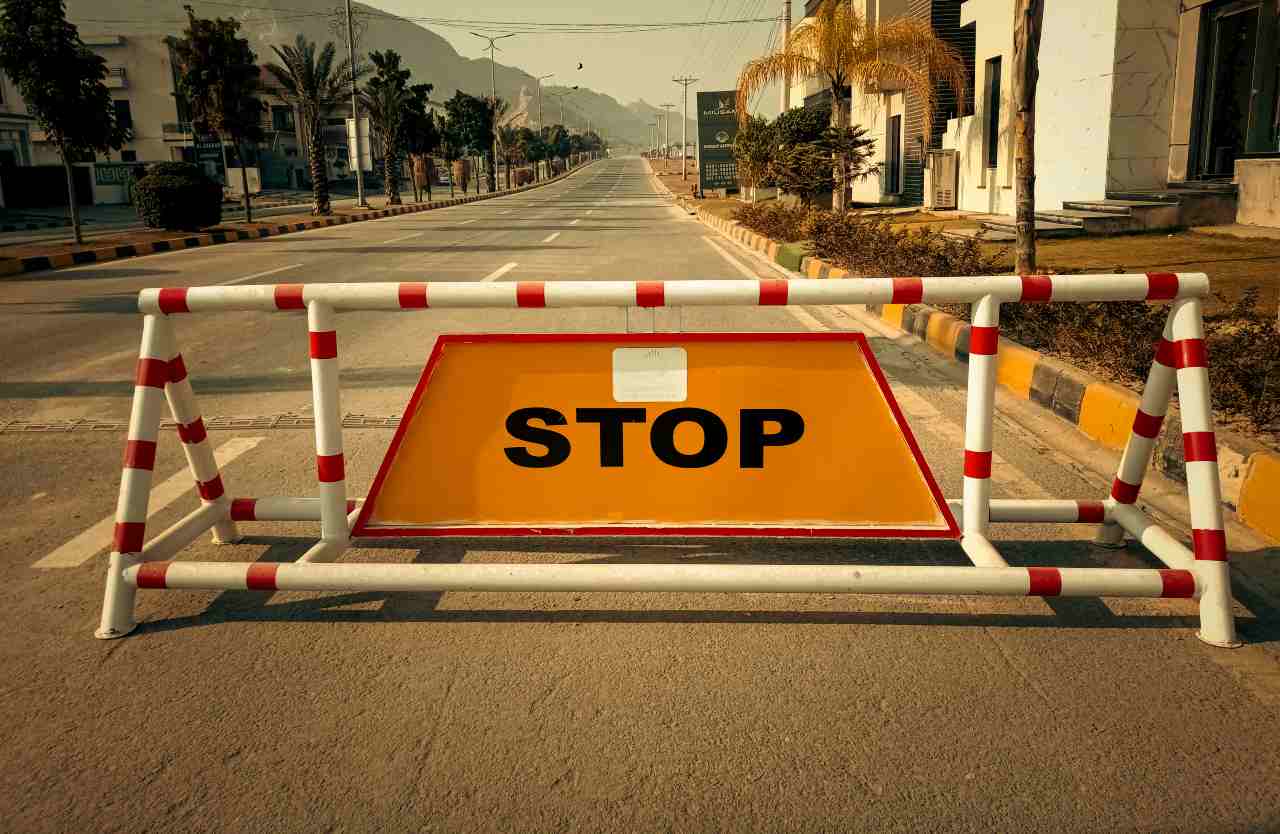 Cartello "stop" retto da transenna in mezzo alla strada