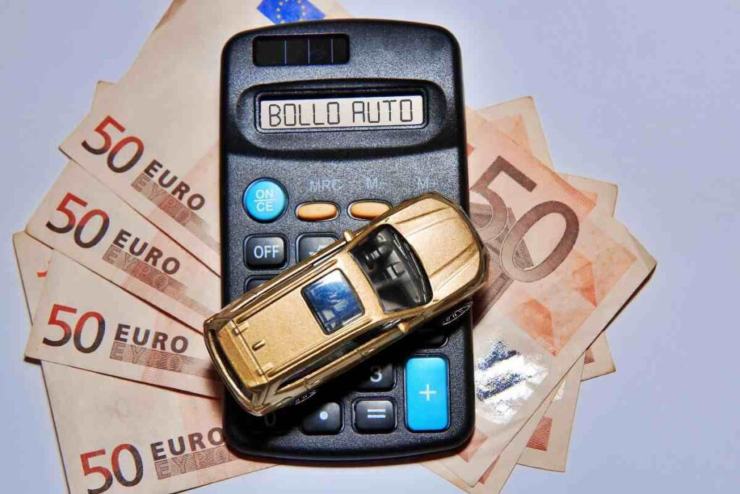 Banconote euro, macchina giocattolo e calcolatrice con su scritto "bollo auto"