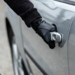 Ladro che apre la portiera di un'auto