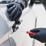 Ladro che scassina la portiera di un'auto