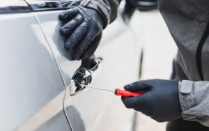 Ladro che scassina la portiera di un'auto