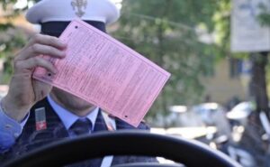 Vigile che mostra una sanzione al conducente attraverso il parabrezza