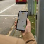 Uomo con lo smartphone vicino ad un ex parcheggio a pagamento con la striscia bianca