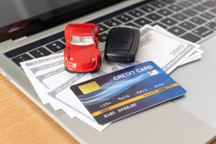 Auto giocattolo sopra tastiera pc assieme a dollari e carta di credito