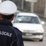 Posto di blocco, agente polizia locale di schiena e auto sullo sfondo