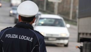 Posto di blocco, agente polizia locale di schiena e auto sullo sfondo