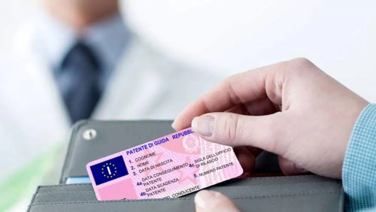 Persona che estrae la patente dal portafoglio e medico sullo sfondo